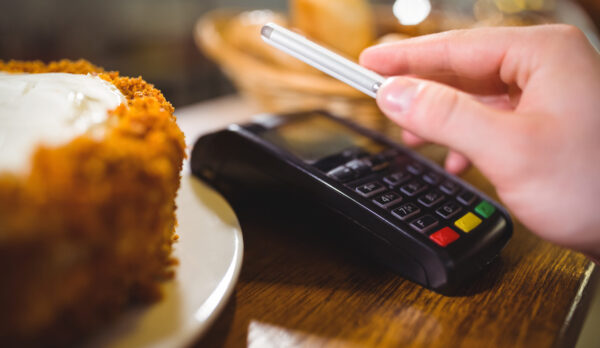 Woman paying bill through smartphone using NFC technology in cafe